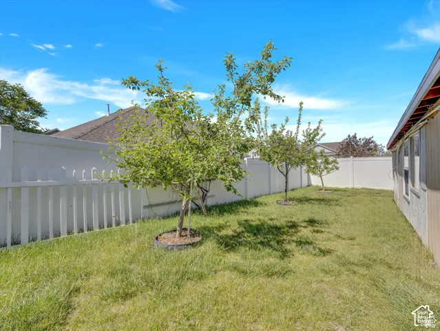 Backyard featuring a lawn, white vinyl fencing, and mature trees