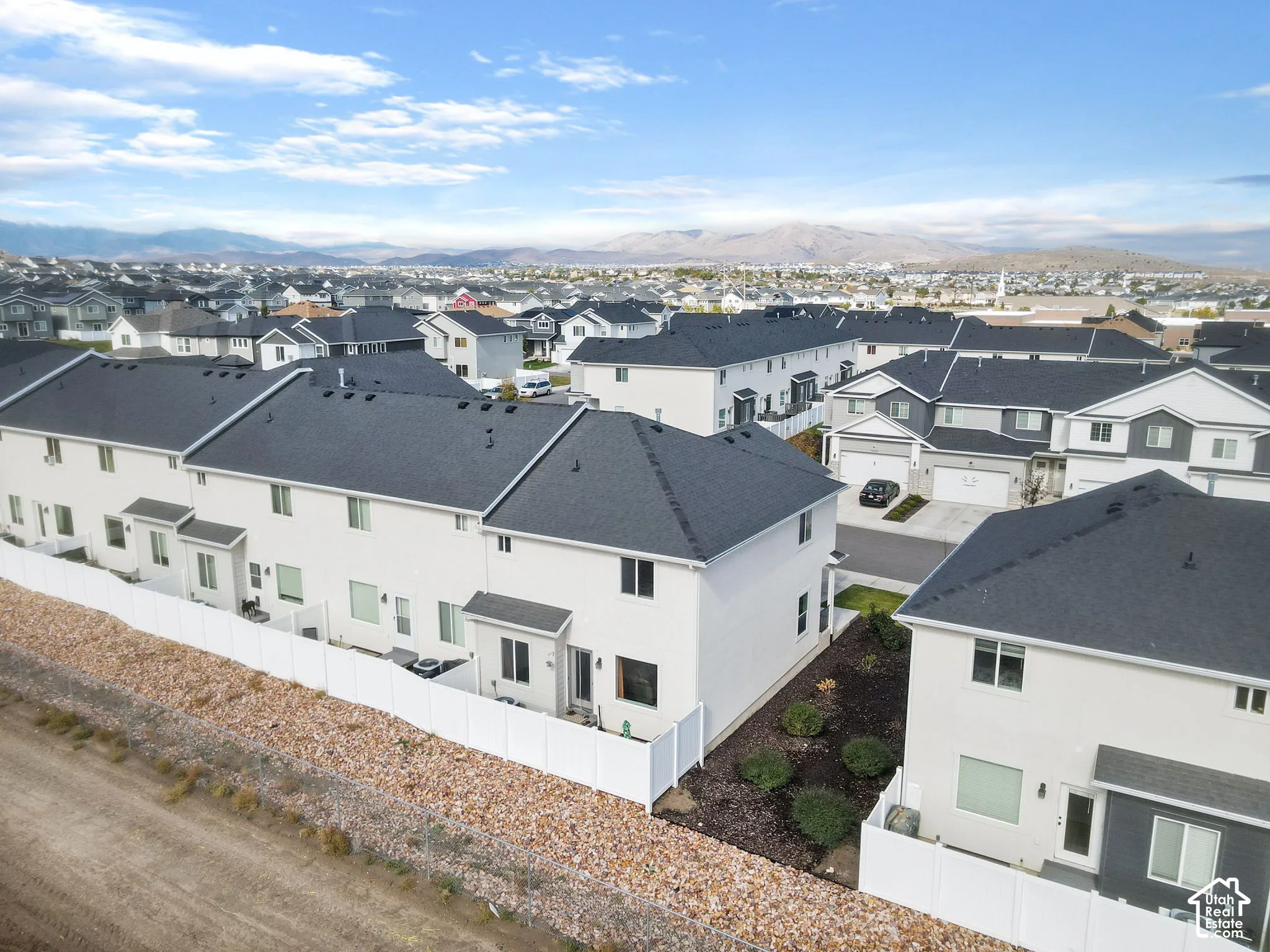 Modern residential community featuring contemporary white exterior finishes, dark asphalt roofing, and multi-unit architecture with clean geometric lines