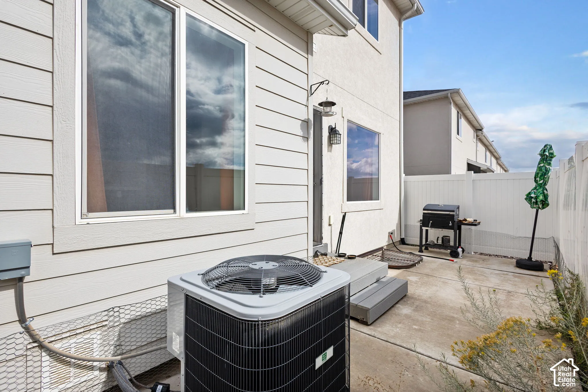 Exterior space featuring horizontal siding, dual-pane windows, a concrete patio, and a perimeter vinyl fence