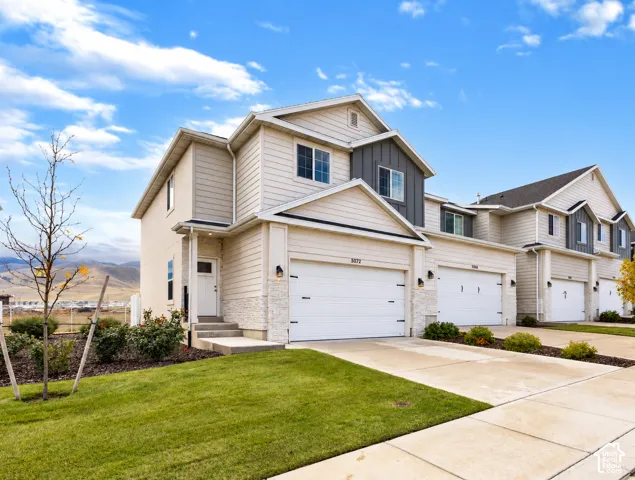 Multi-level exterior featuring horizontal lap siding, vertical board-and-batten accents, stone veneer foundation, two-car garage, and concrete driveway