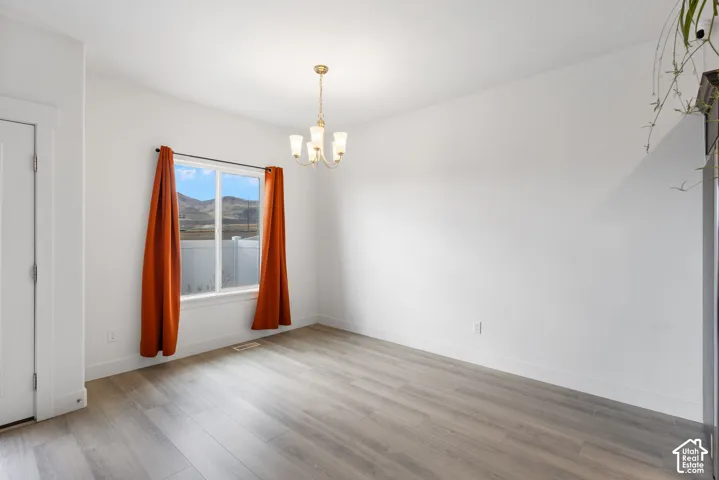 Wood-finish flooring, multi-light chandelier, and large window with mountain scenery