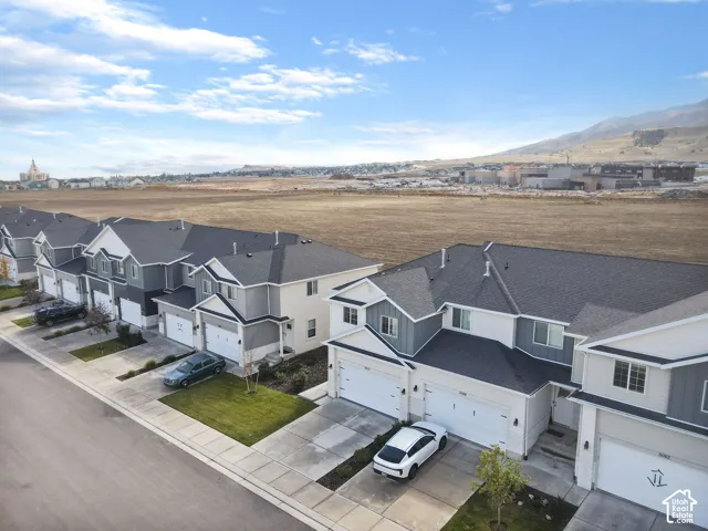 Multi-unit residential complex featuring gabled rooflines, two-tone neutral siding, paved private driveways, and integrated garages