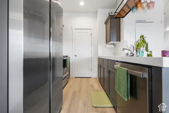 Kitchen featuring stainless steel appliances, dark wood-finish cabinetry, solid surface countertops, and wood-finish flooring