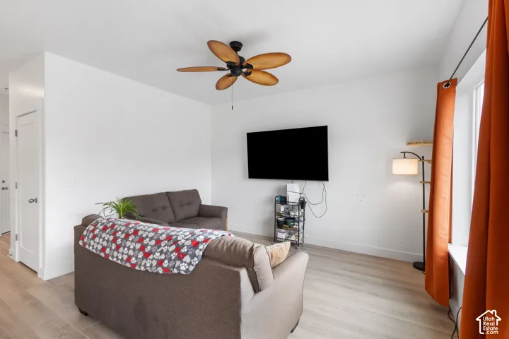 Neutral interior space featuring wood-finish flooring, a ceiling-mounted fan with five curved blades, and a solid-core interior door