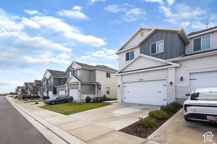 Multi-story exterior featuring a mix of horizontal lap siding and vertical board-and-batten accents, stone veneer foundation details, attached two-car garage, and concrete driveway