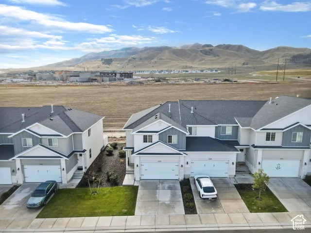 Multi-unit exterior featuring vertical and horizontal siding, asphalt shingle roofing, concrete driveways, and mountain backdrop