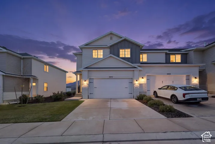 Multi-story exterior featuring horizontal lap siding, vertical board-and-batten accents, stone veneer foundation detailing, and an attached two-car garage