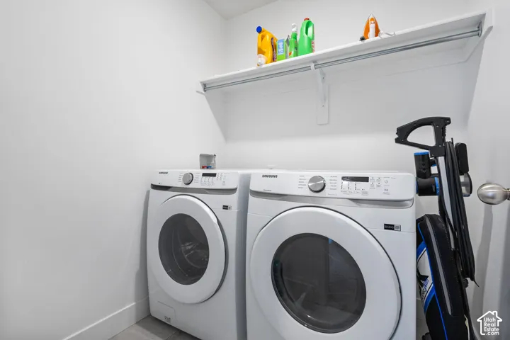Laundry area featuring white front-load appliances and a mounted upper storage shelf with integrated hanging rod