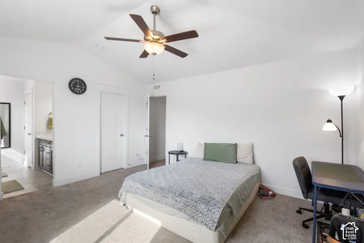 Spacious bedroom with ceiling fan, carpeted flooring, and abundant natural light