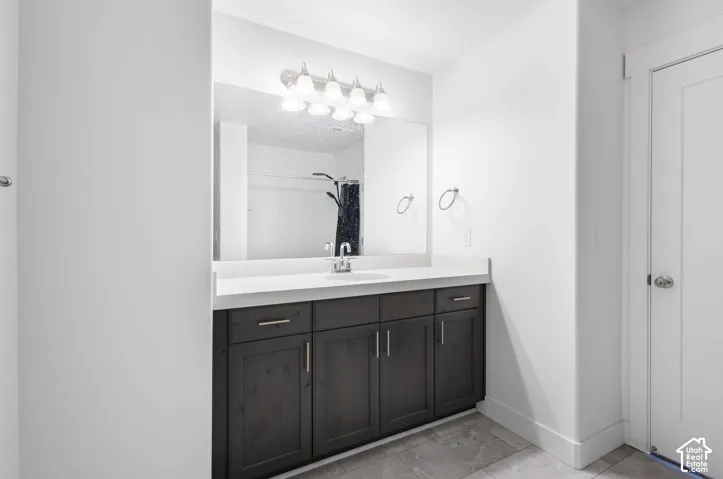 Spa-inspired master bathroom featuring a dark cabinetry vanity with brushed gold hardware, white quartz countertop, and an oversized framed mirror
