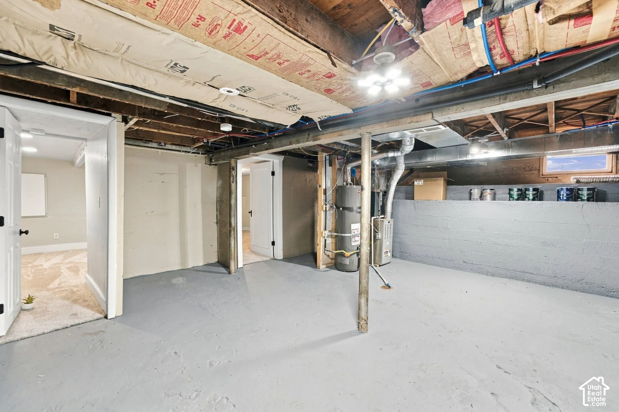 Unfinished lower level featuring exposed joist ceiling, painted concrete flooring, masonry perimeter walls, and utility mechanicals