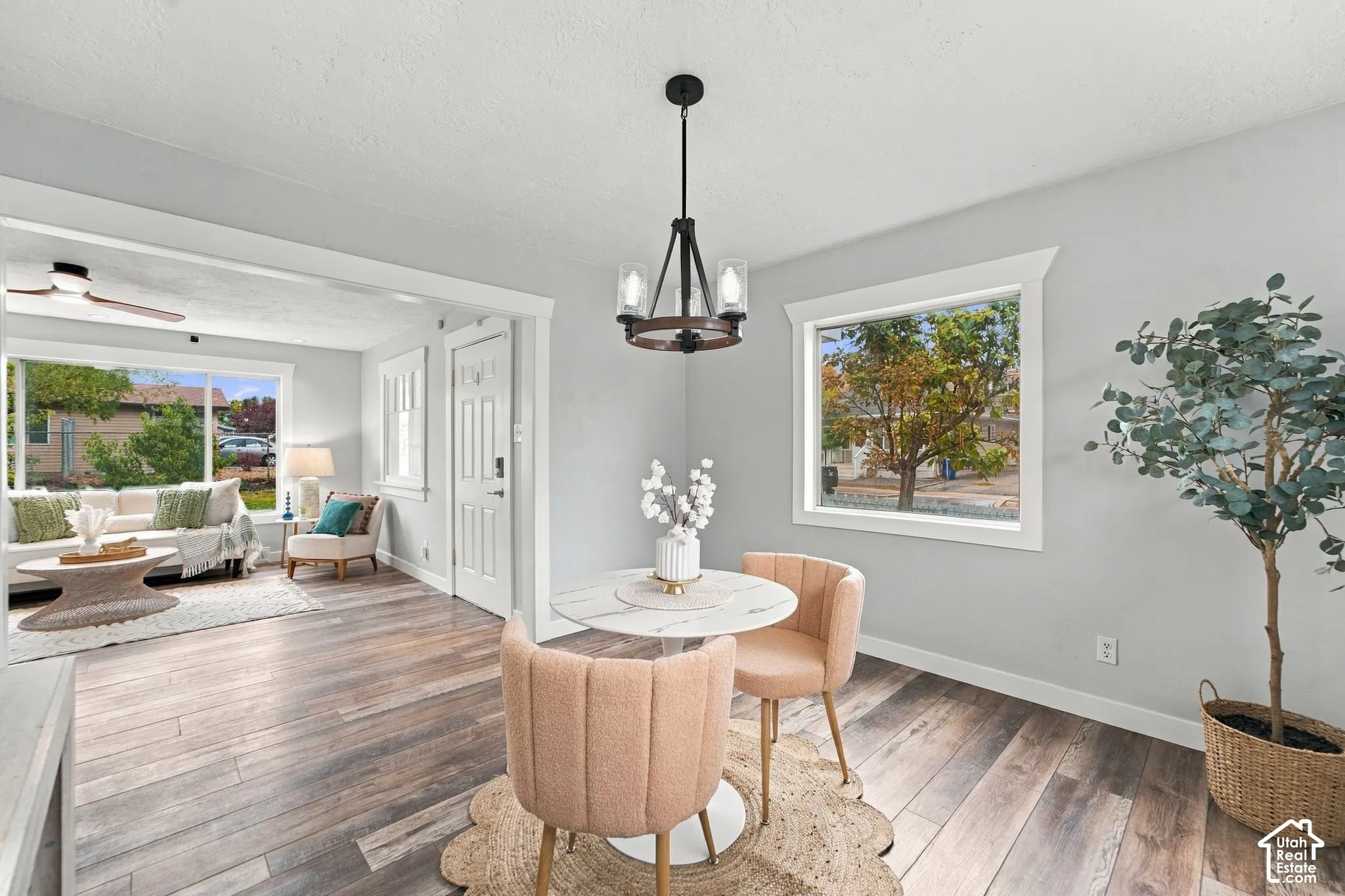 Dining area featuring wood-finish flooring, a multi-arm chandelier with glass shades, and large picture windows with white casing