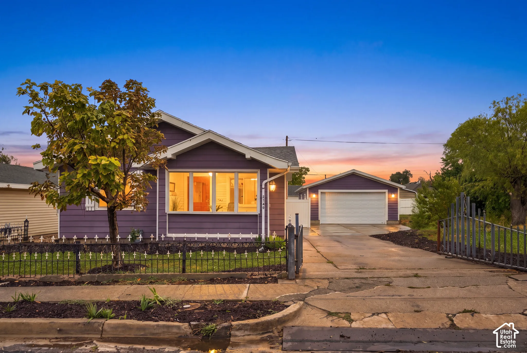 Single-story residence featuring lap siding, an expansive front window, a detached garage, and a gated driveway with iron fencing