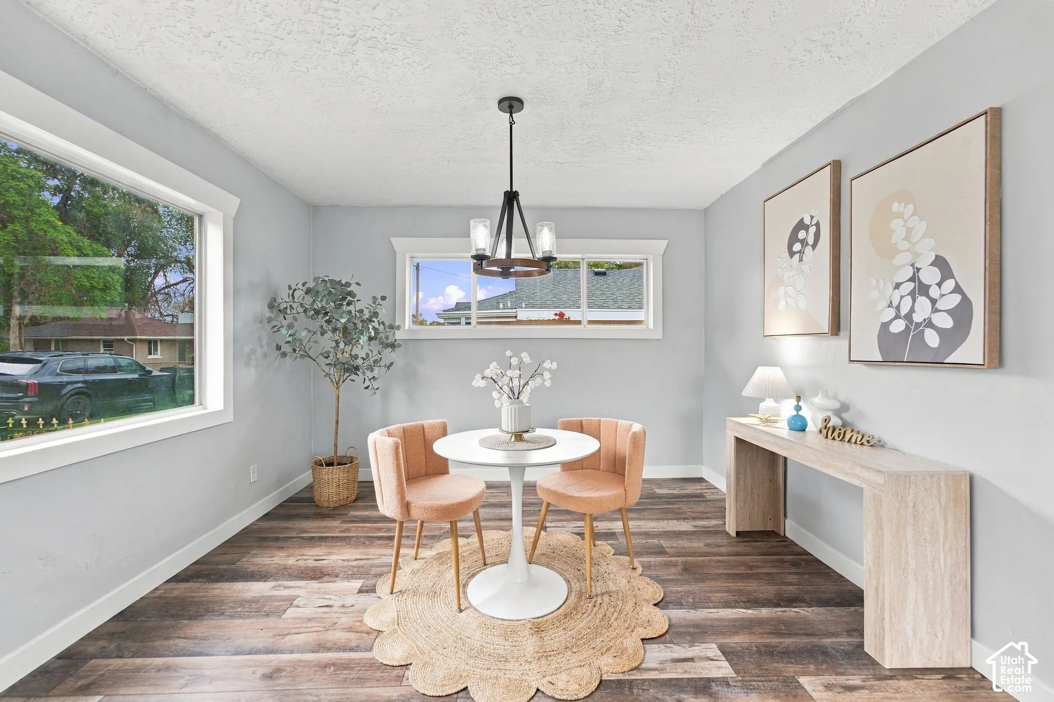Neutral interior with wood-finish flooring, crisp window casings, and a multi-light chandelier