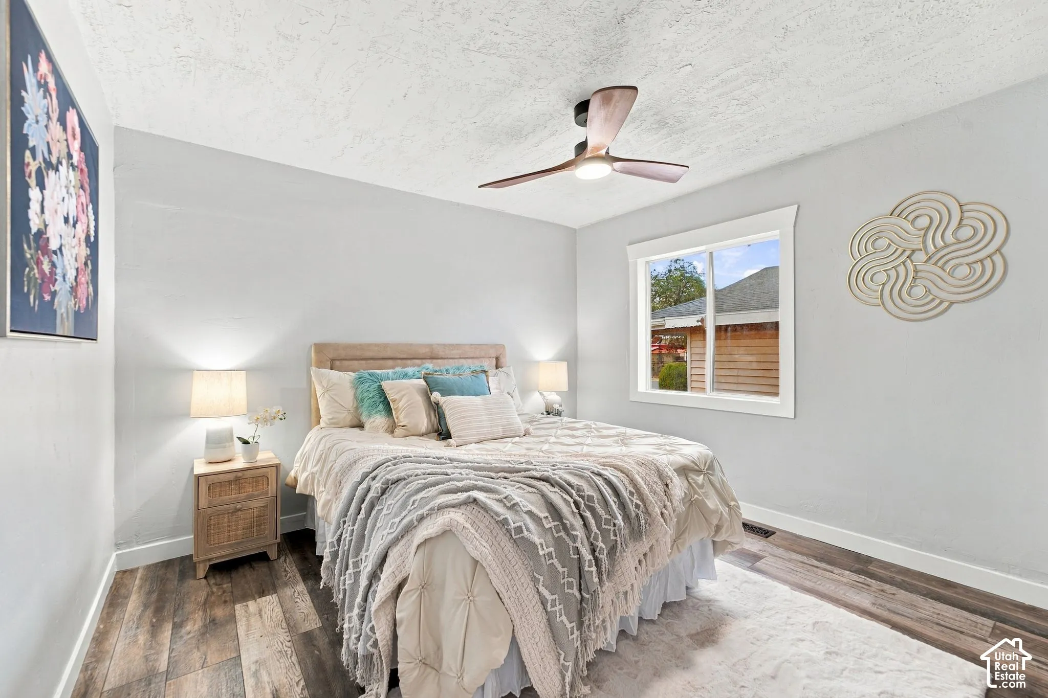 Bedroom featuring wood-finish flooring, textured ceiling, and a modern three-blade ceiling fan with integrated lighting