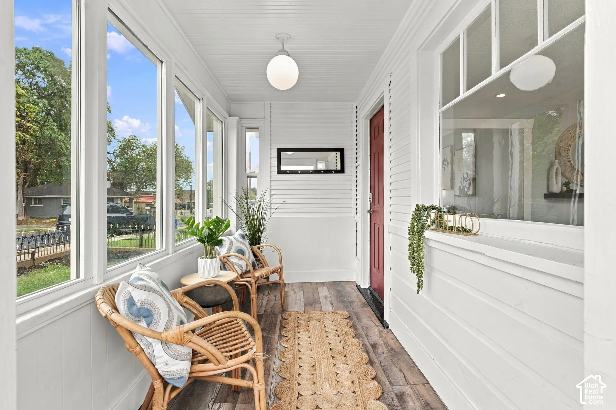 Enclosed porch featuring horizontal shiplap siding, wood-finish flooring, multi-pane windows, and a globe pendant light fixture