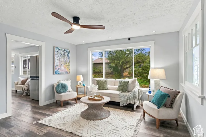 Living area featuring wood-finish flooring, a modern three-blade ceiling fan with integrated lighting, recessed ceiling lights, and expansive windows