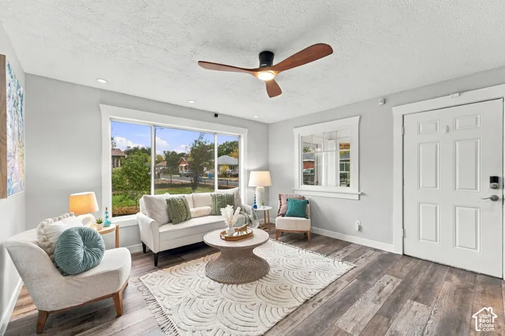 Wood-finish flooring, neutral wall tones, multi-pane window, flush-mounted ceiling fan with light fixture, and paneled entry door