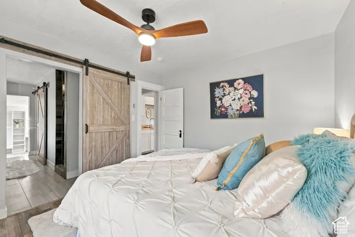 Interior featuring a wood-finish barn door with black hardware, three-blade ceiling fan with light kit, and multi-panel interior door