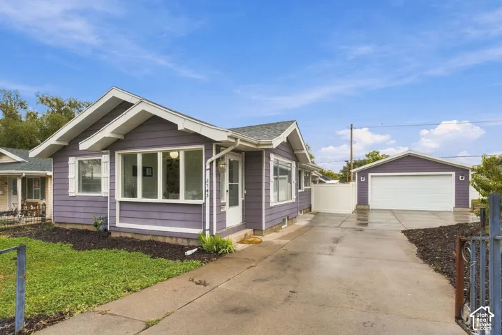 Single-story exterior with horizontal siding, a gabled roofline, multi-pane windows, a concrete driveway, and a detached garage