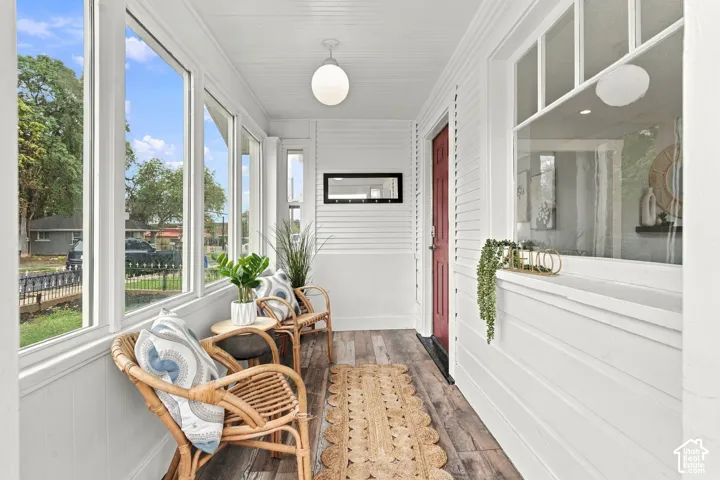 Enclosed porch featuring horizontal shiplap siding, wood-finish flooring, multi-pane windows, and a globe pendant light fixture