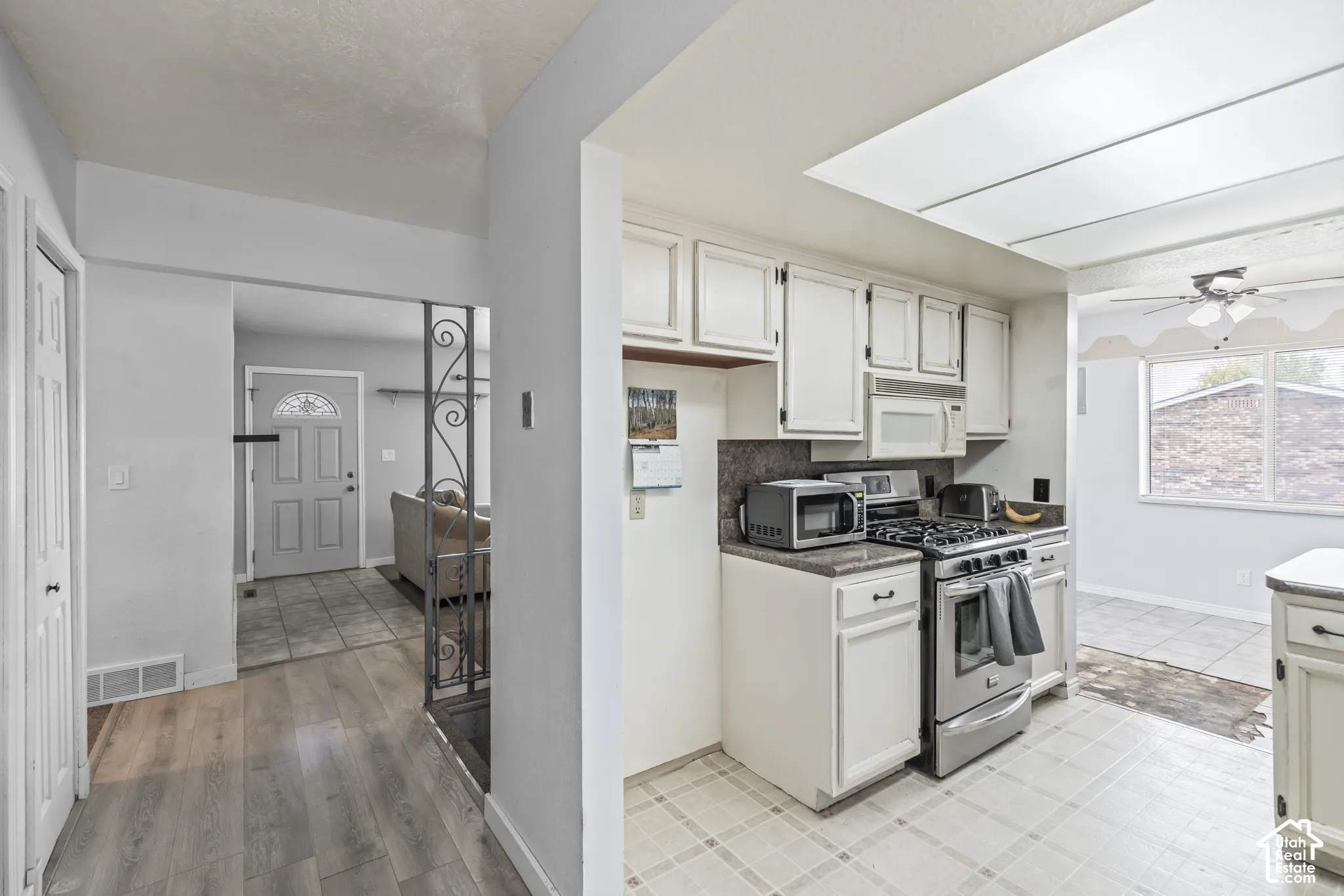 Kitchen featuring white cabinetry, stainless steel range and microwave, recessed lighting, and tile flooring