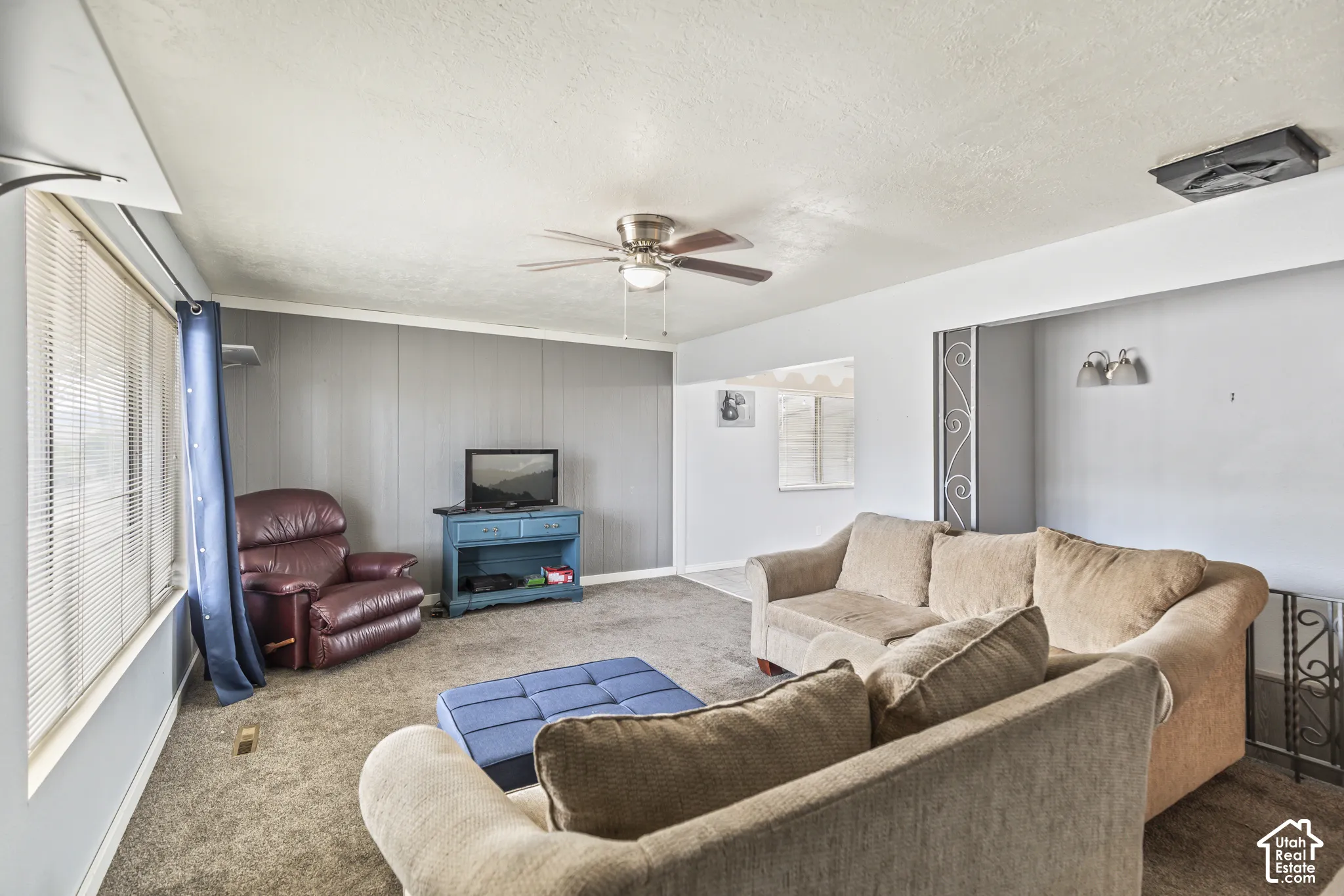 Interior space featuring a ceiling fan, neutral wall-to-wall carpeting, and an accent wall with paneling