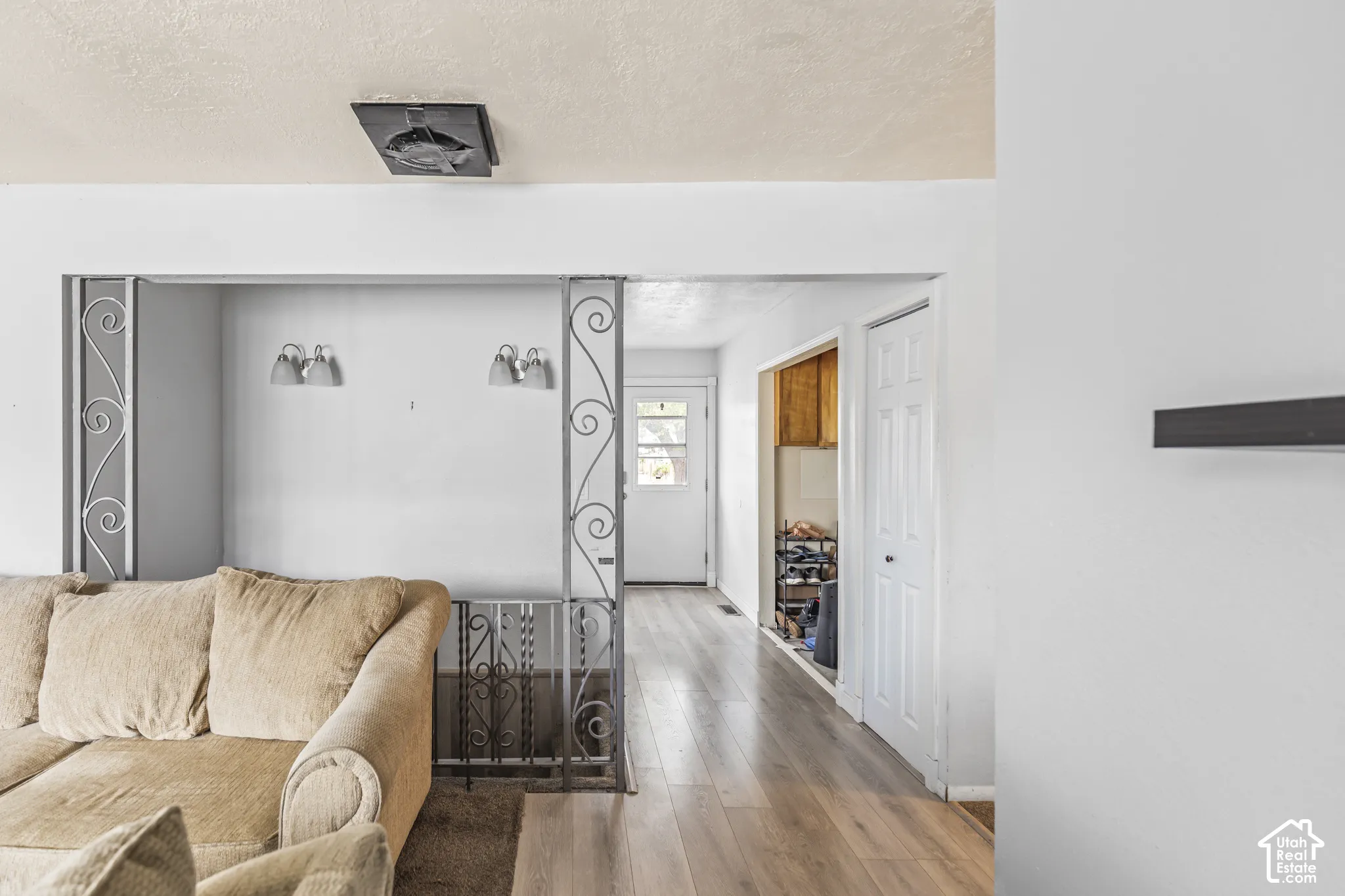 Wood-finish flooring throughout, decorative wrought iron balustrade, dual wall-mounted light fixtures, and multi-panel interior doors