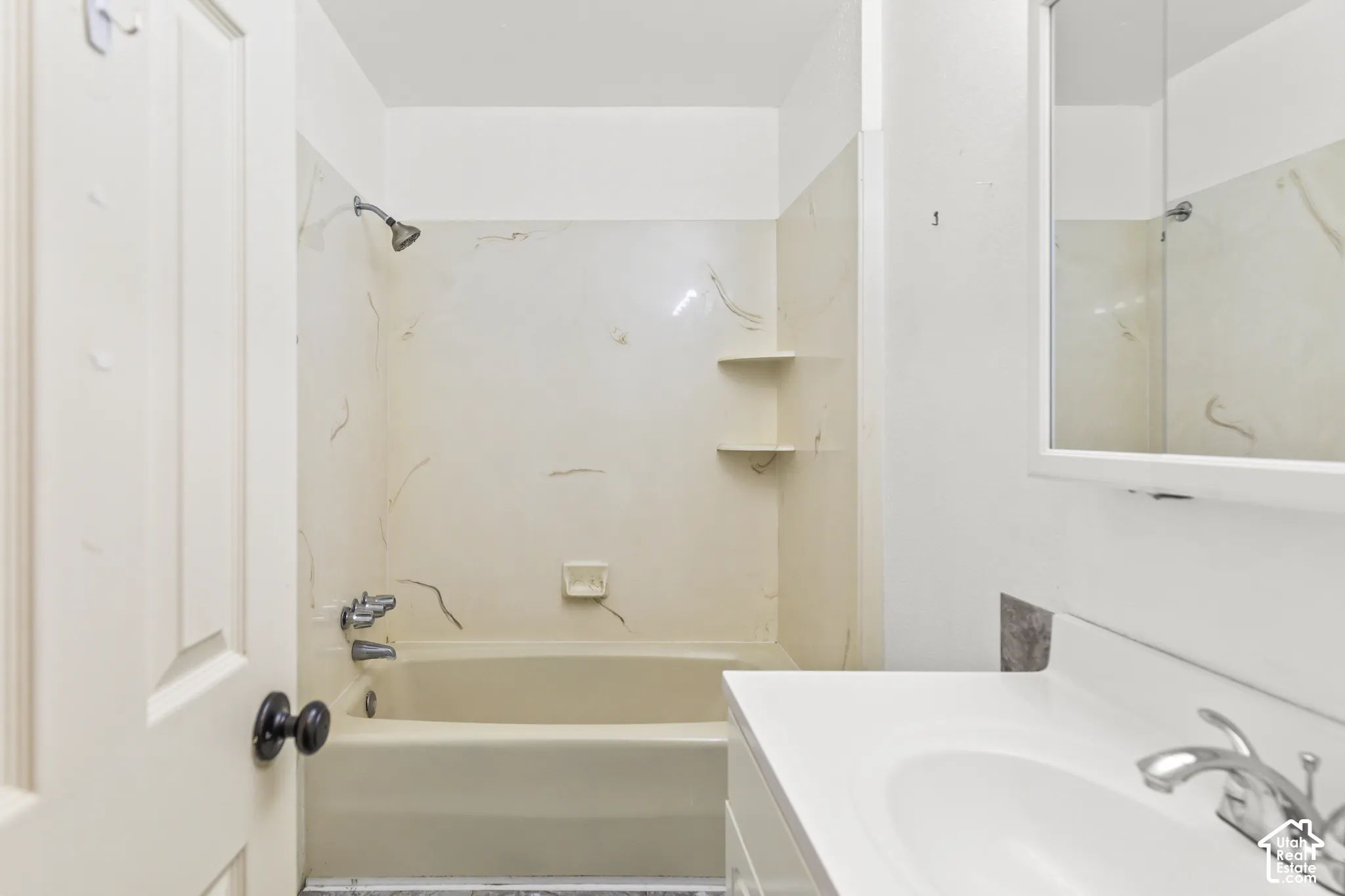 Bathroom featuring a tub-and-shower combination with integrated wall shelving, a vanity with a white molded countertop, an integrated sink, and a wall-mounted medicine cabinet