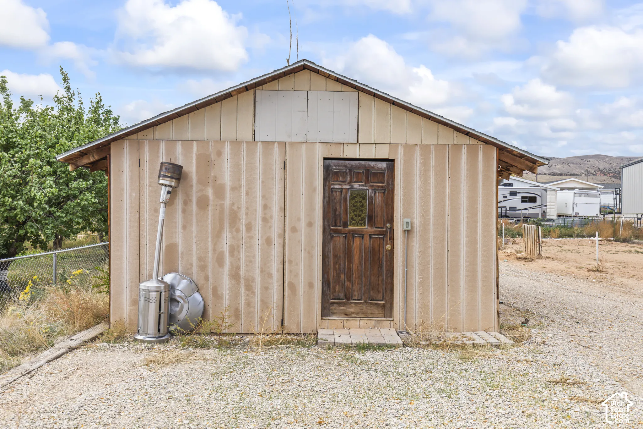 Detached structure featuring vertical wood-composite siding, a gable roofline, and a solid wood entry door with a decorative glass insert