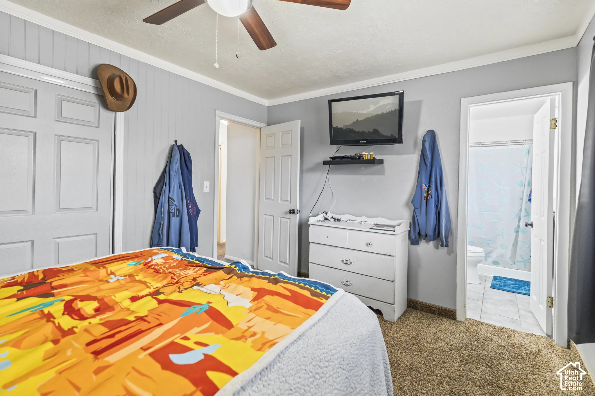 Bedroom featuring wall-paneling detail, ceiling fan with light fixture, and carpeted flooring