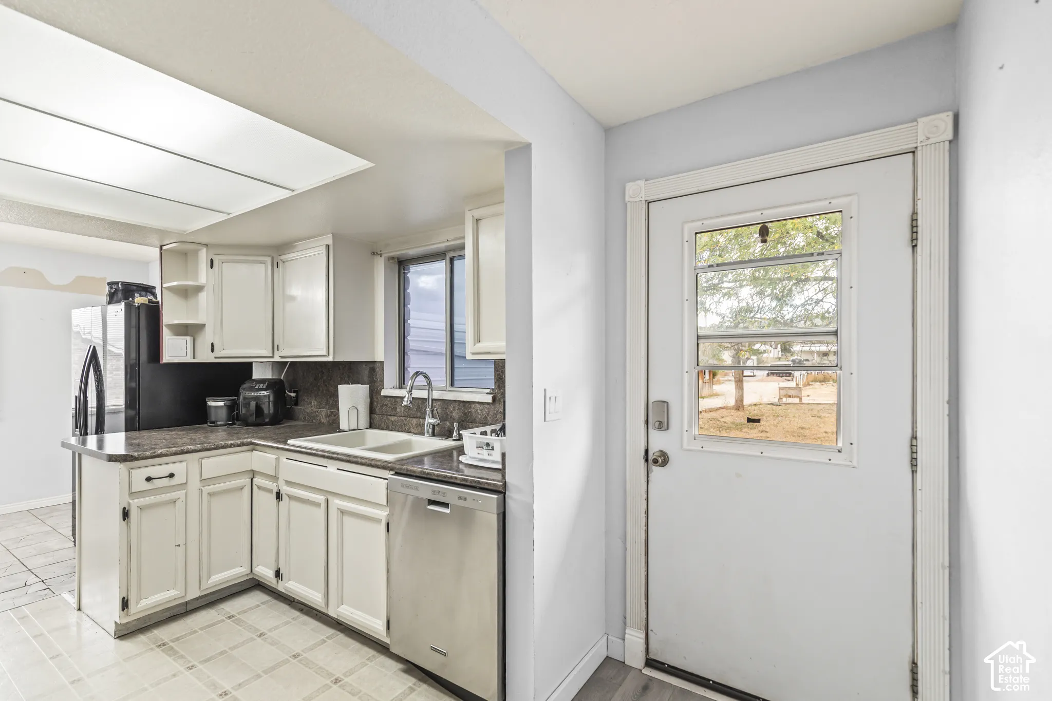 Kitchen featuring white shaker-style cabinetry, stainless steel dishwasher, dual-basin sink with arched faucet, and stone-finish countertops