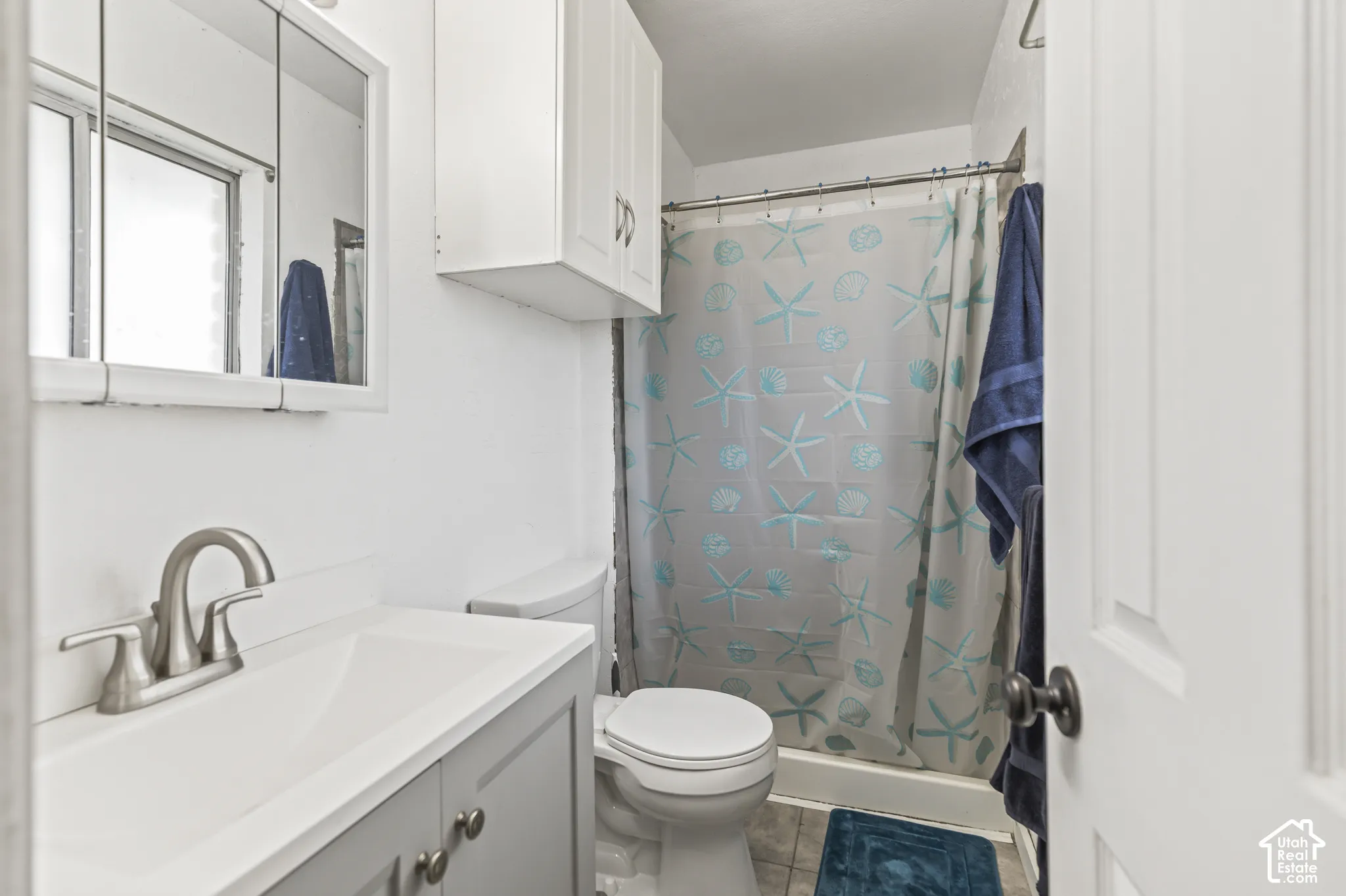 Bathroom featuring a vanity with integrated sink, brushed-nickel finish faucet, wall-mounted storage cabinetry, medicine cabinet, and a tub-shower combination