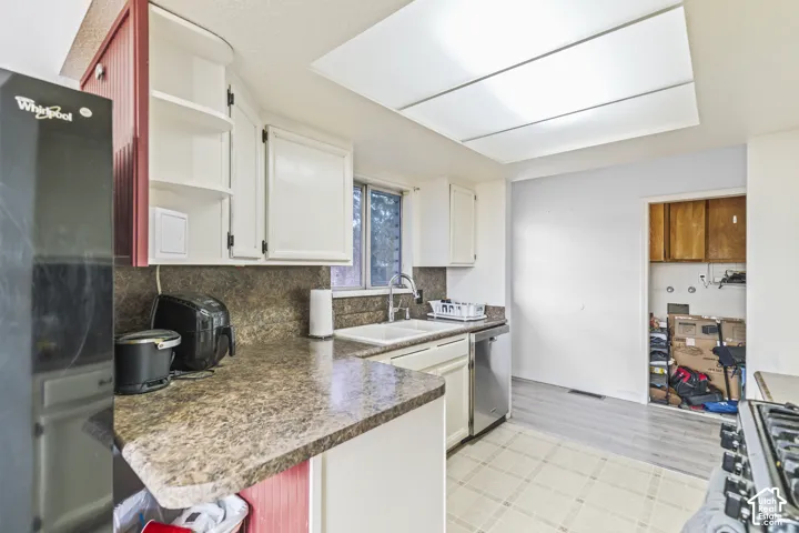 Kitchen featuring laminate countertops, dual-basin sink with gooseneck faucet, stainless steel dishwasher, and painted cabinetry