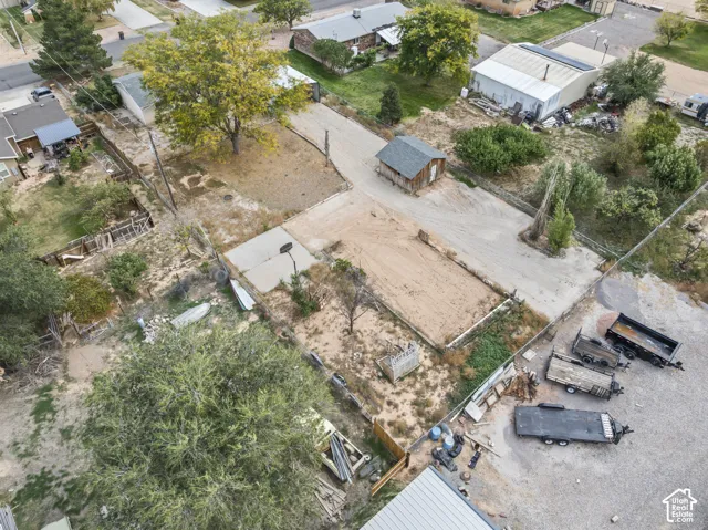 Expansive lot featuring mature trees, a detached storage shed, gravel driveway, and chain-link fencing