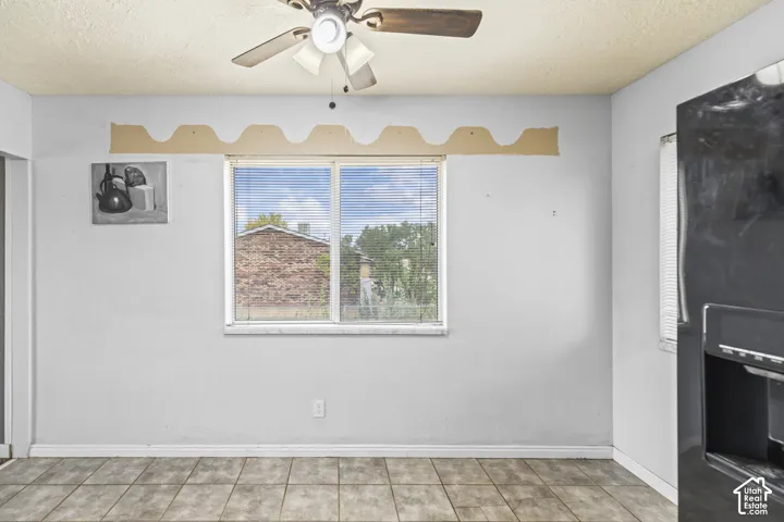 Single-hung window with horizontal blinds, ceiling fan with light fixture, and tiled flooring