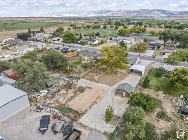 Expansive acreage featuring a detached storage structure, a covered carport, a gravel driveway, and prominent mountain backdrops