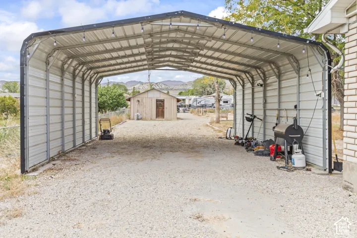 Covered metal carport with a gravel surface and exterior mountain backdrop