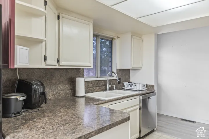Kitchen featuring white cabinetry, solid-surface countertops with an integrated backsplash, double-basin sink with a gooseneck faucet, stainless steel dishwasher, and recessed ceiling lighting