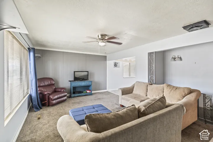 Interior space featuring a ceiling fan, neutral wall-to-wall carpeting, and an accent wall with paneling