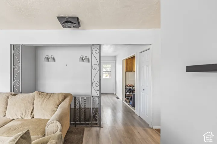 Wood-finish flooring throughout, decorative wrought iron balustrade, dual wall-mounted light fixtures, and multi-panel interior doors