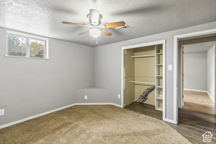 Room featuring wall-to-wall carpeting, a ceiling fan with integrated lighting, a built-in corner ledge, and a closet with integrated shelving