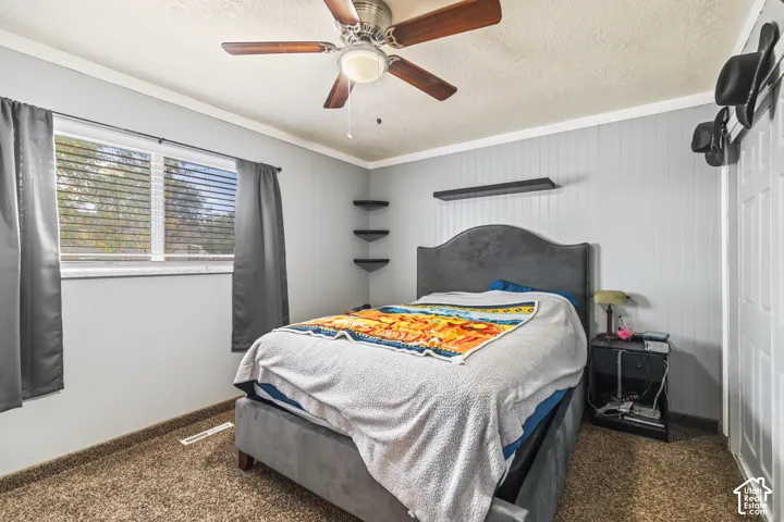 Room featuring plank-style wall paneling, a ceiling fan with integrated lighting, built-in corner shelving, and a horizontal wall-mounted shelf