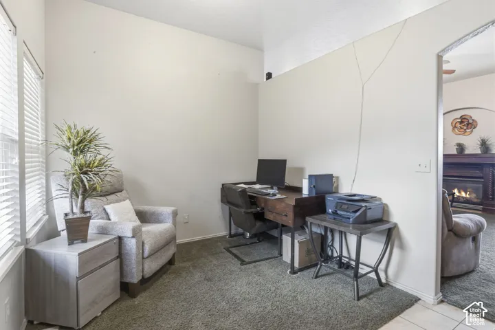 High-ceilinged interior room featuring neutral wall tones, carpeted flooring, and a wide arched entryway