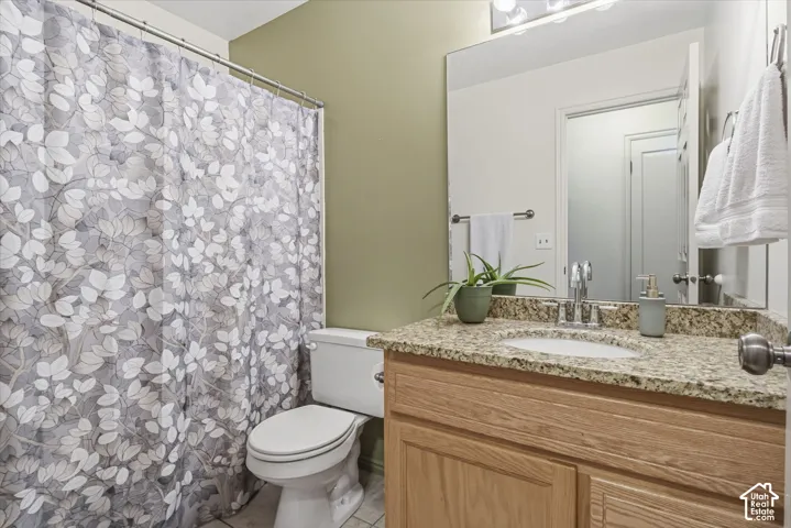 Bathroom featuring a stone-look countertop with an integrated oval sink, light wood cabinetry, a large wall-mounted mirror, and a full-height shower enclosure
