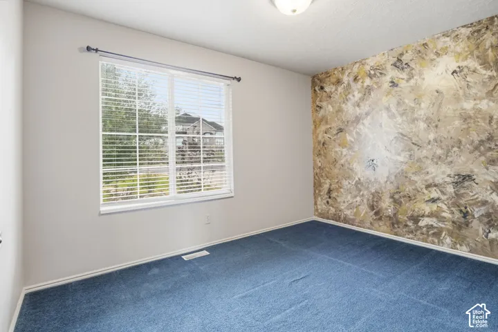 Room featuring a multi-tonal decorative accent wall, wall-to-wall carpeting, and a multi-pane window with blinds