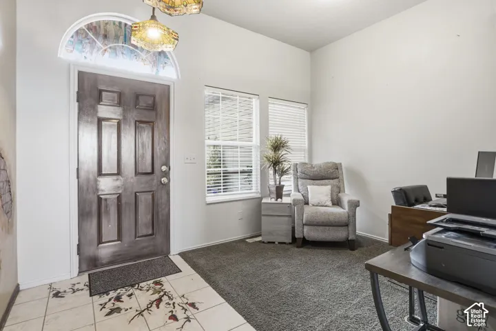 Entryway featuring a solid panel front door, arched decorative transom window, inset tile flooring, and dual pendant light fixtures