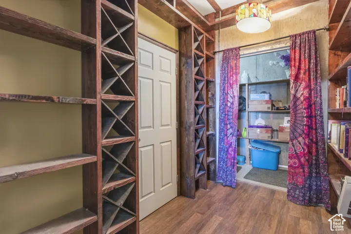 Custom built-in wood shelving featuring X-frame wine storage and open display units, wood-finish flooring, and a stained glass pendant light fixture