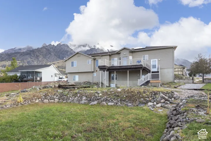 Two-story residence featuring horizontal siding, a raised deck with railing, and a mountain backdrop
