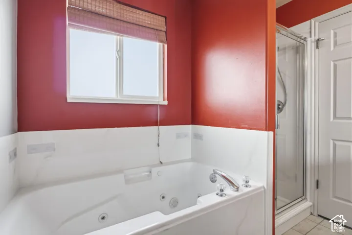 Jetted soaking tub with stone-finish surround, separate glass-enclosed shower, and polished chrome fixtures